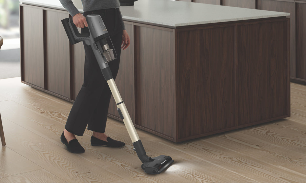 Electrolux Stick Vacuum with vacuum head light on, used on a wooden floor in kitchen