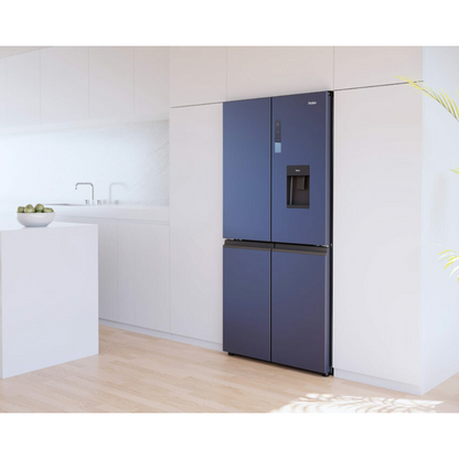 Angle view of the Haier 507L quad door fridge with the doors closed in a black finish, in a modern kitchen setting with white cabinetry showing the flat door design, electric controls and water and ice dispenser.