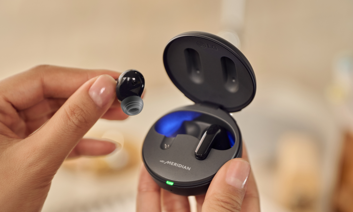 LG headphones with meridian being held in someones hands with the blue UV light visible in the case