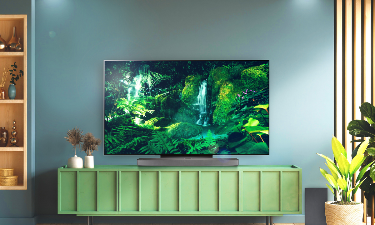 LG Oled Television with lush greenery on the screen sitting on a green cabinet in a lounge