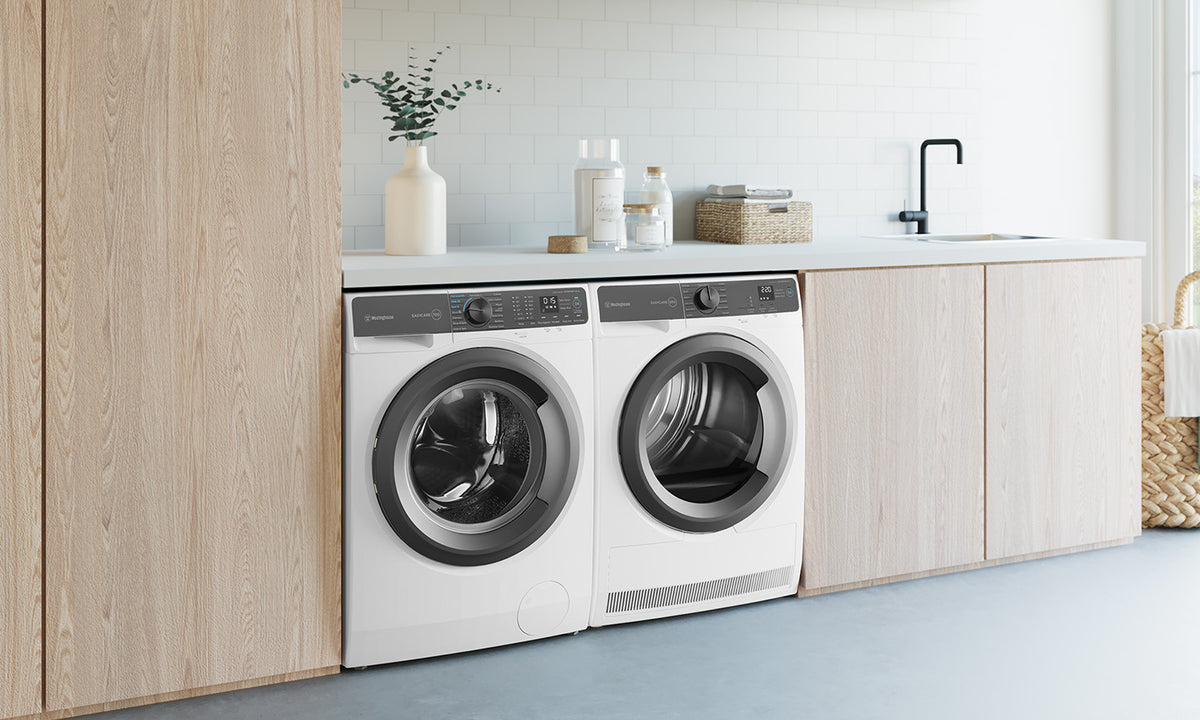 Westinghouse washing machine and dryers beside each other in a wood paneled laundry with a white countertop