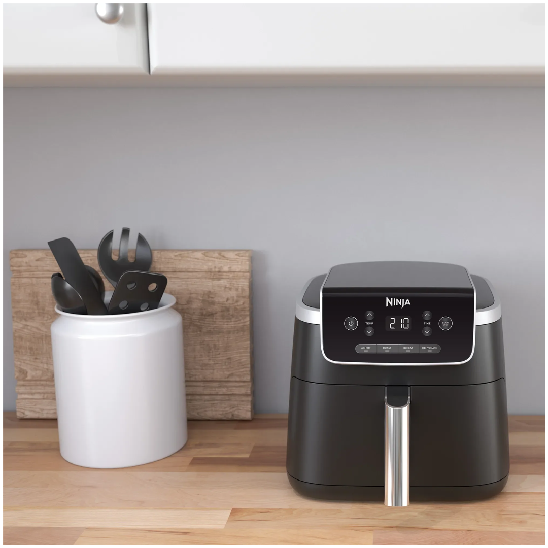 Ninja air fryer on a kitchen counter with utensils in the background