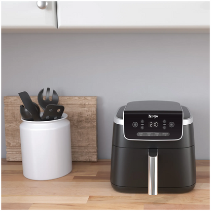Ninja air fryer on a kitchen counter with utensils in the background