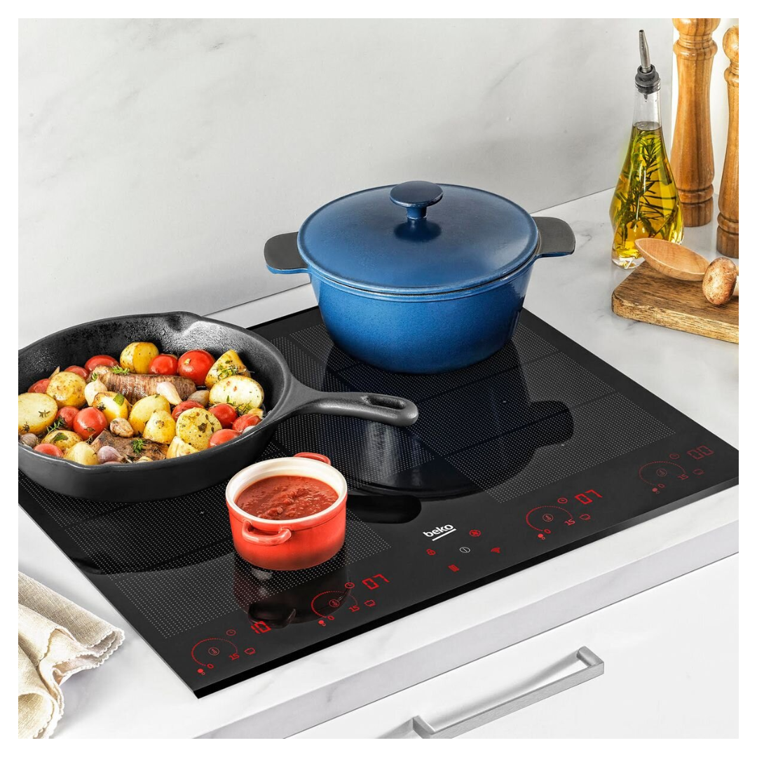 A modern Beko 60cm black glass induction cooktop with red LED touch controls is shown in use. Three pots are on the cooktop: a red pot with tomato sauce, a black cast iron skillet with roasted vegetables, and a large blue pot with a lid. Olive oil, wooden utensils, and seasoning containers are placed nearby on a wooden board, creating a stylish and functional kitchen setting.