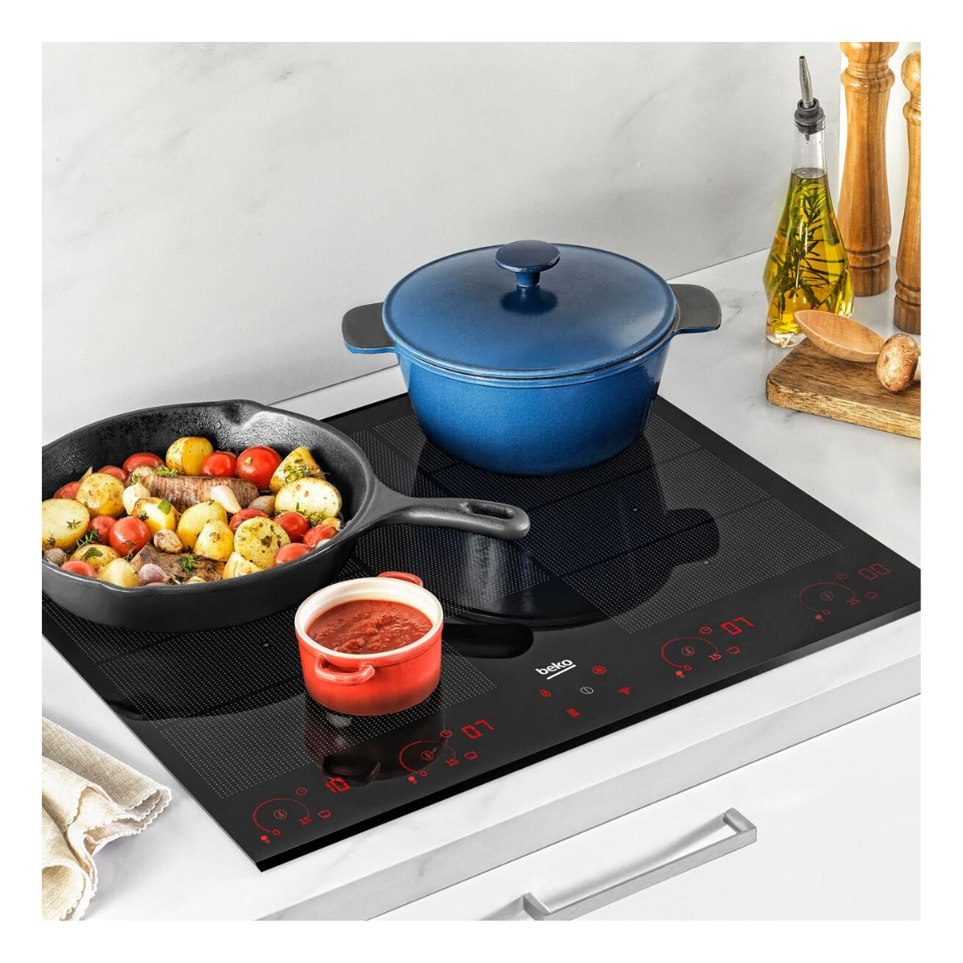 Beko 90m 6 zones Induction Cooktop with luminous controls pictured in a modern kitchen setting with food being prepared on it 
