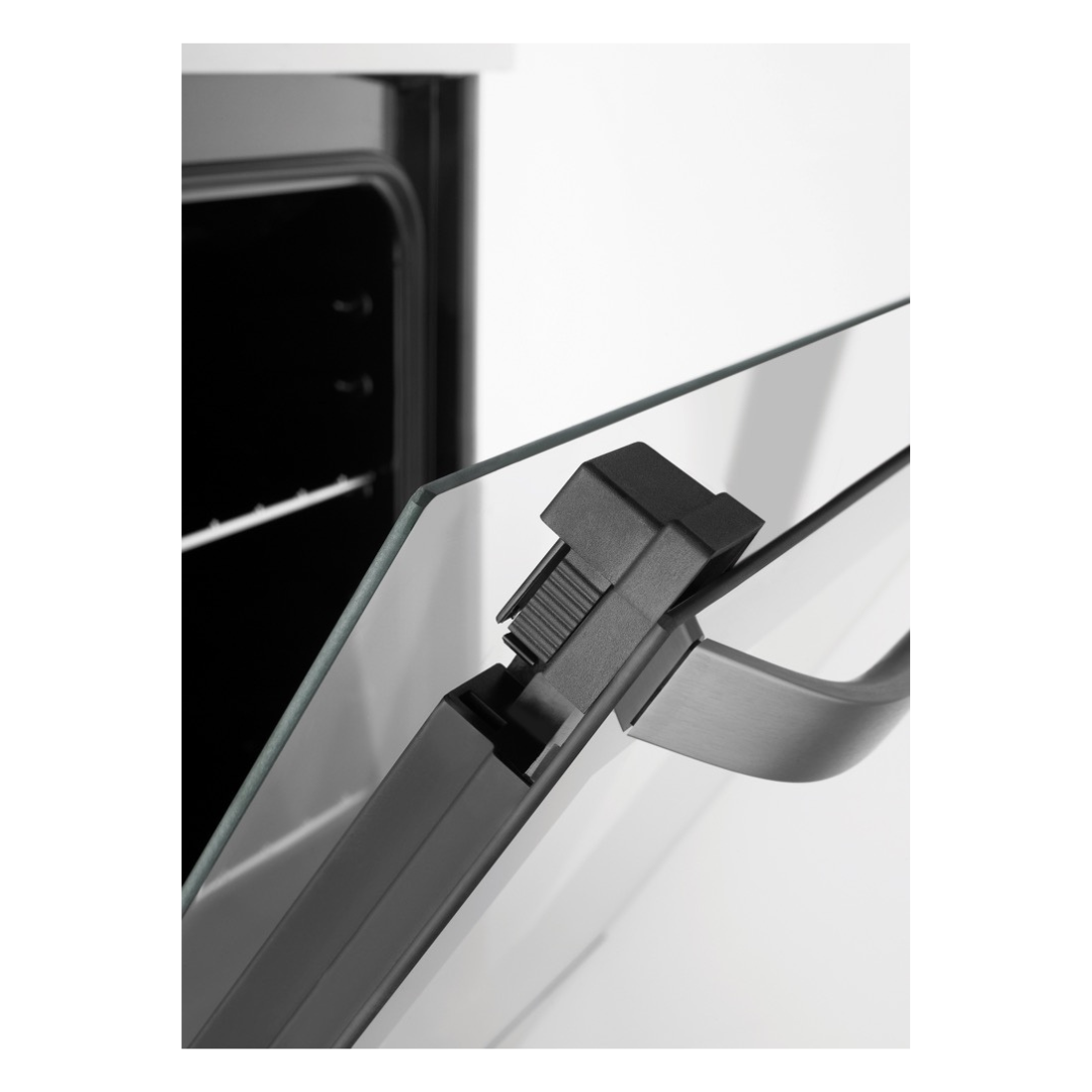Close up view of the oven door slightly opened, showing the thickness of the glass as well as the handle.