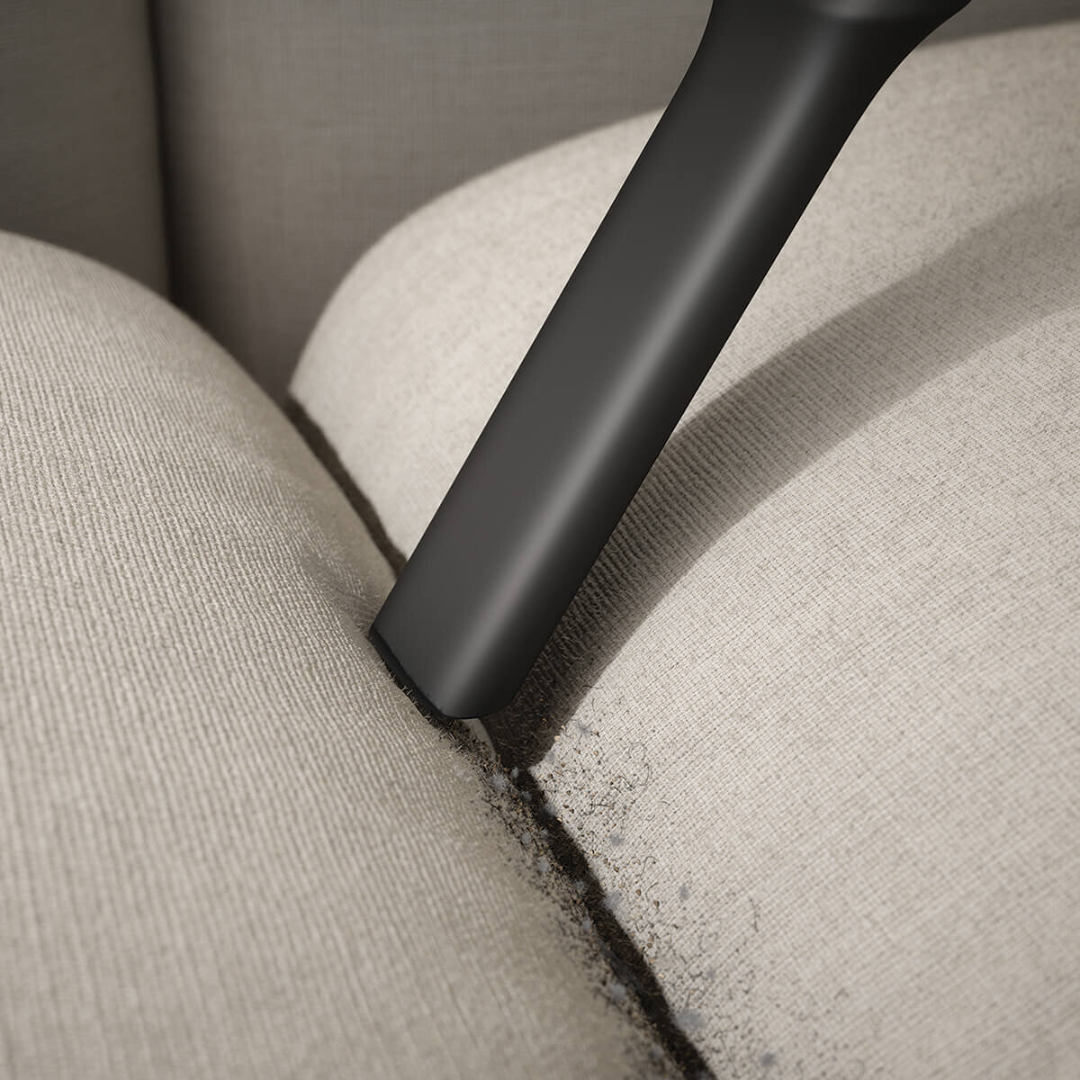 Close up view of the Electrolux 600 series cordless stick vacuum using the crevice tool to get in between the couch crevices.