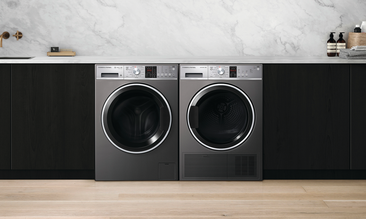 Black laundry cabinets span the width of the image, and in the center is a washing machine and dryer duo in stainless steel