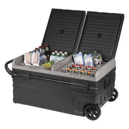 Angled view of the Brass Monkey dual lid portable fridge/freezer with wheels and telescopic handle, stocked with drinks and food, ideal for camping, road trips, or outdoor adventures.  
