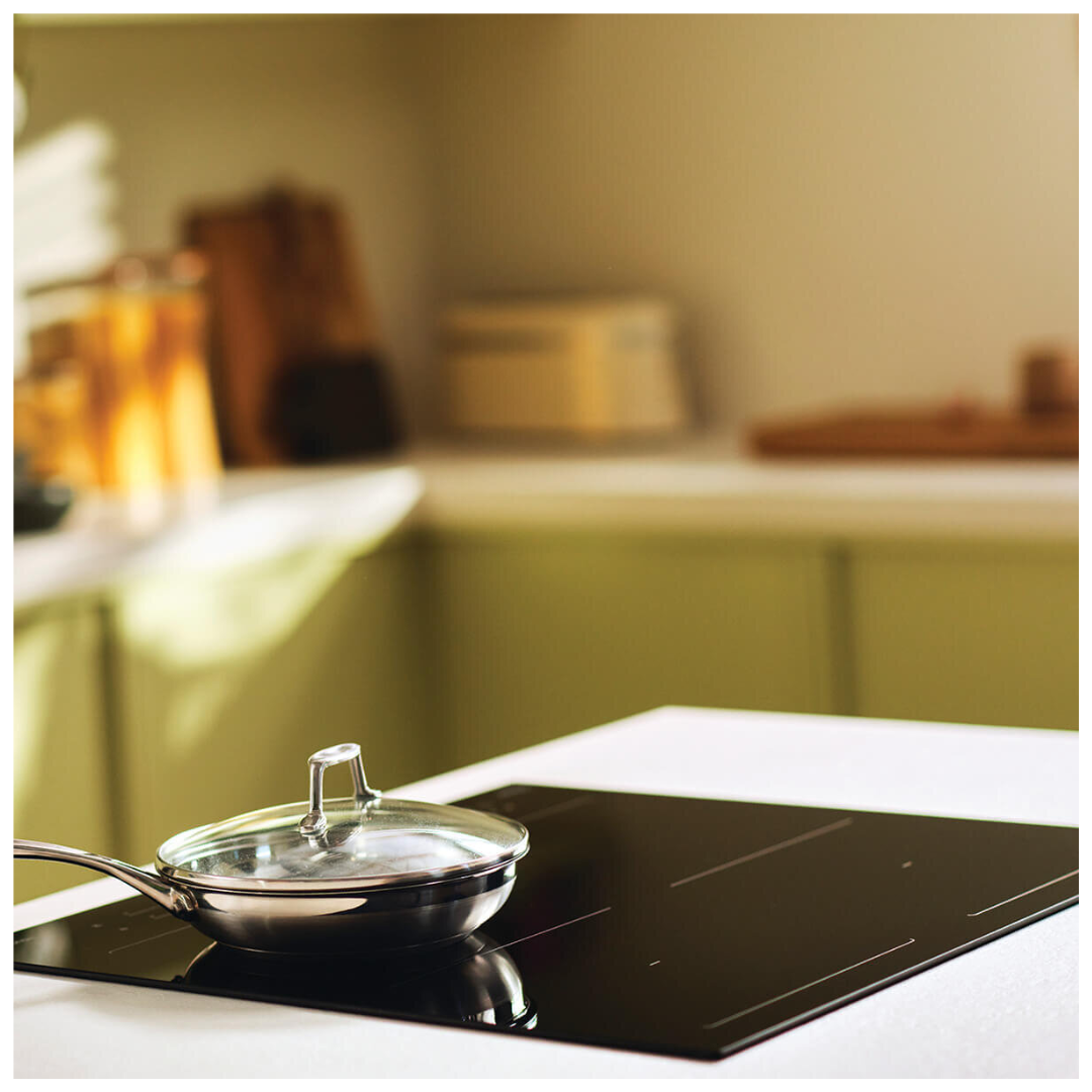 Angle view of Haier induction cooktop with a pan on the cooktop in a modern kitchen setting. 