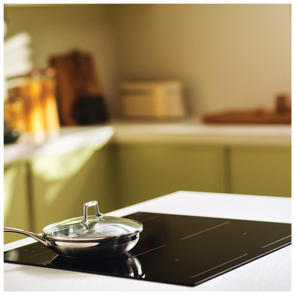 Angle view of Haier induction cooktop with a pan on the cooktop in a modern kitchen setting. 