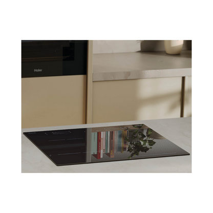 Lifestyle image of the Haier induction cooktop installed on a marble benchtop with a Haier oven in the background. 
