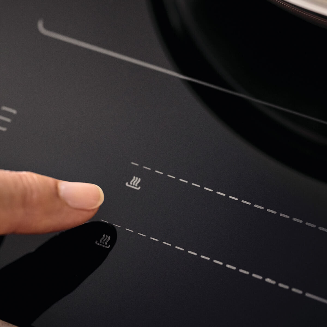 Person's finger making use of the touch controls on the Haier induction cooktop. 