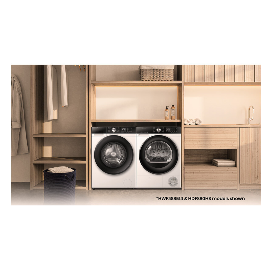 Front view of the Hisense 8.5kg front load washing machine next to a Hisense dryer, in a modern laundry set up with wooden cabinetry and detergents on the table top above them. 
