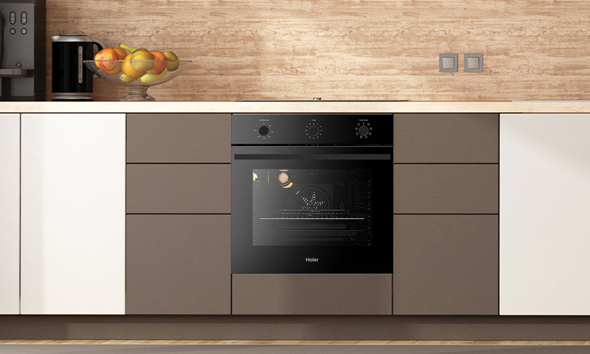 A Haier Black Oven is built into a brown kitchen cabinet in a wooden looking kitchen
