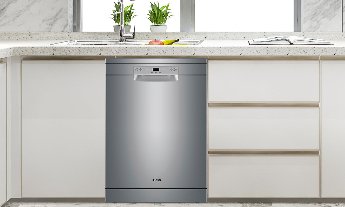 A Haier Stainless Steel Dishwasher sits under a stone white counter top in a white kitchen