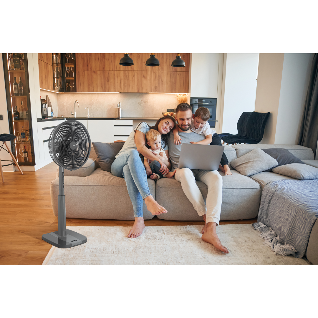 Family sitting on a couch with a laptop next to a standing fan in a living room showcasing the Mitsubishi Electric pedestal fan.