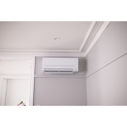 White Mitsubishi Electric air conditioning unit mounted on a wall in a room with a neutral color scheme.