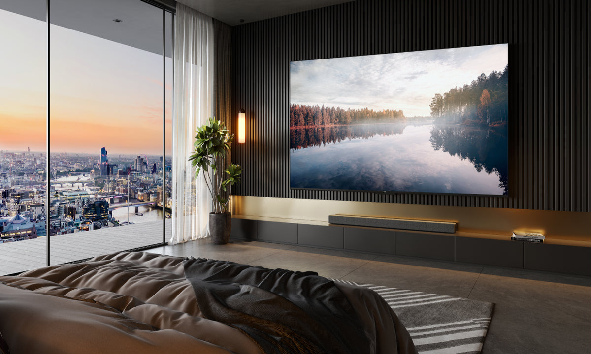 A large flat screen Ultra HD Television by TCL featured in a bedroom with big glass windows overlooking the city